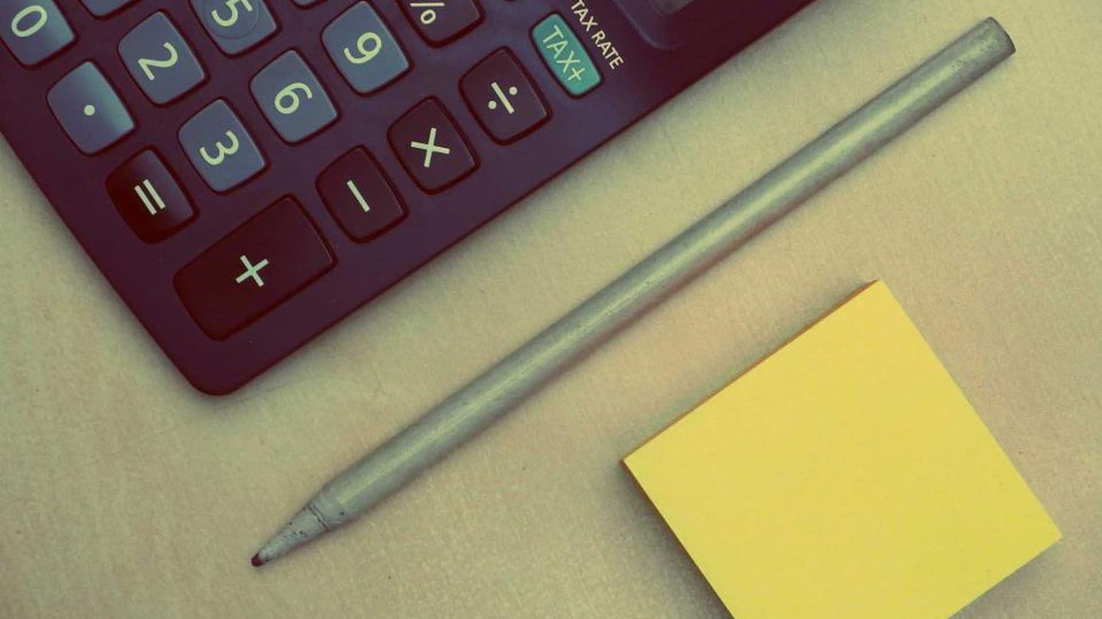 Calculadora, lápis e bloco de notas amarelo sobre uma superfície clara
