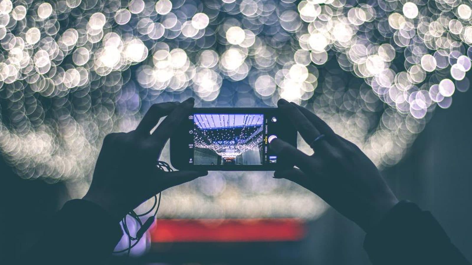 Mãos segurando um celular que grava uma cena iluminada