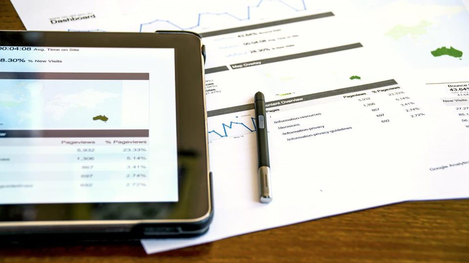 Tablet com gráficos e relatórios impressos sobre uma mesa de madeira