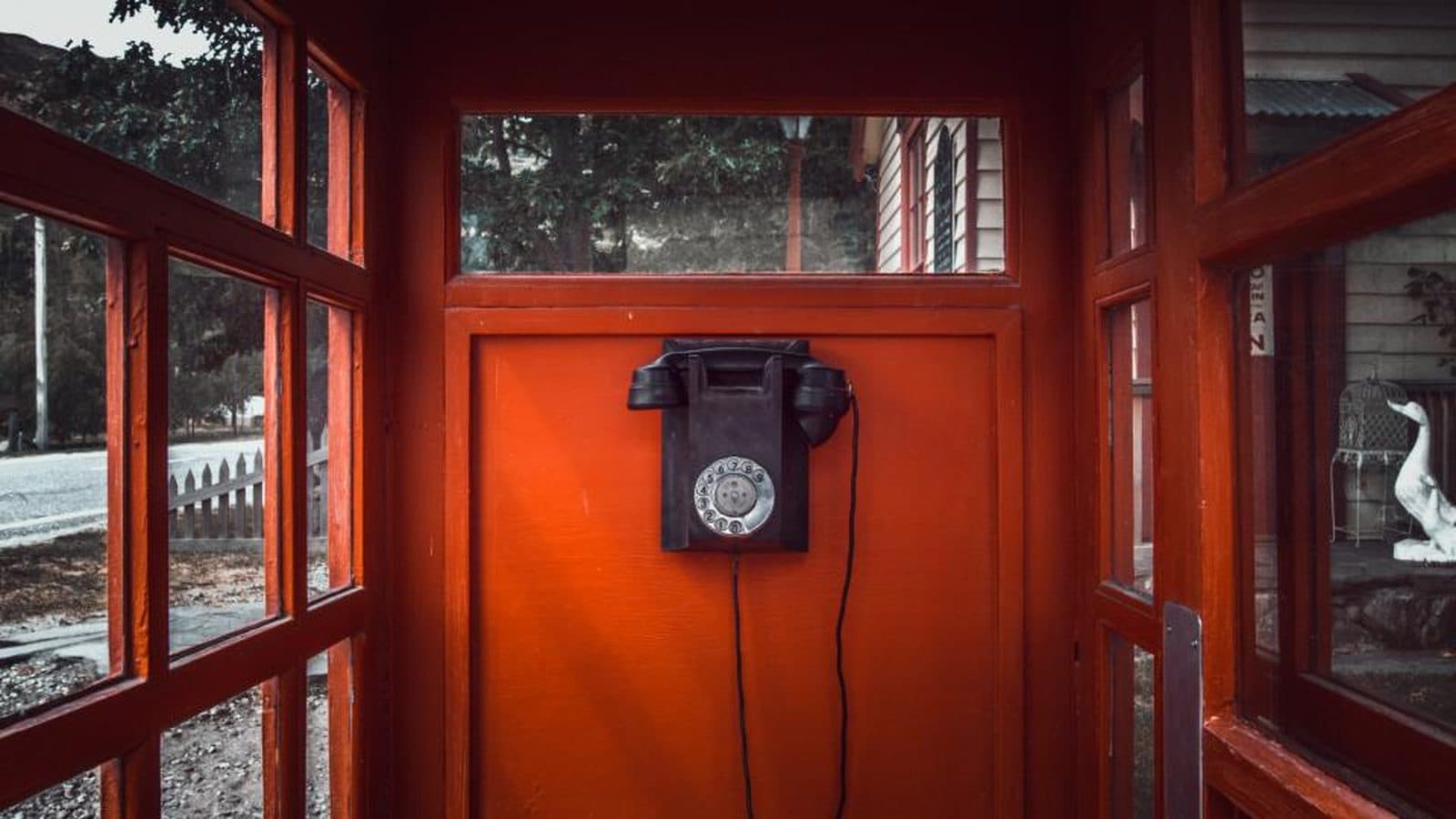 Cabine telefônica antiga, com aparelho de disco na parede