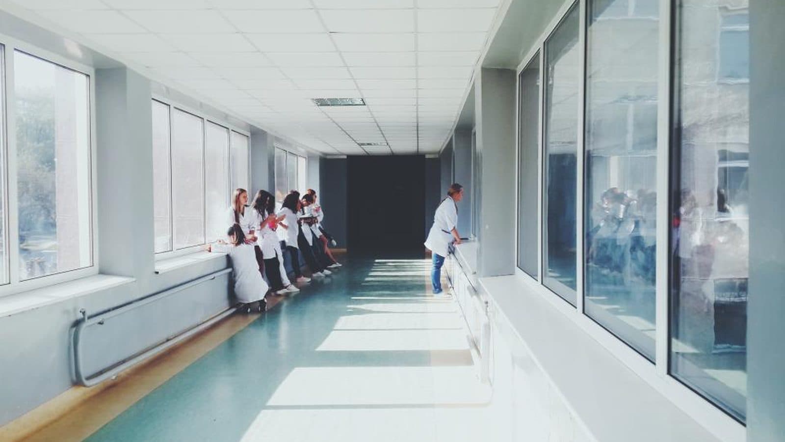 Corredor iluminado de uma clínica, com pessoas ao fundo