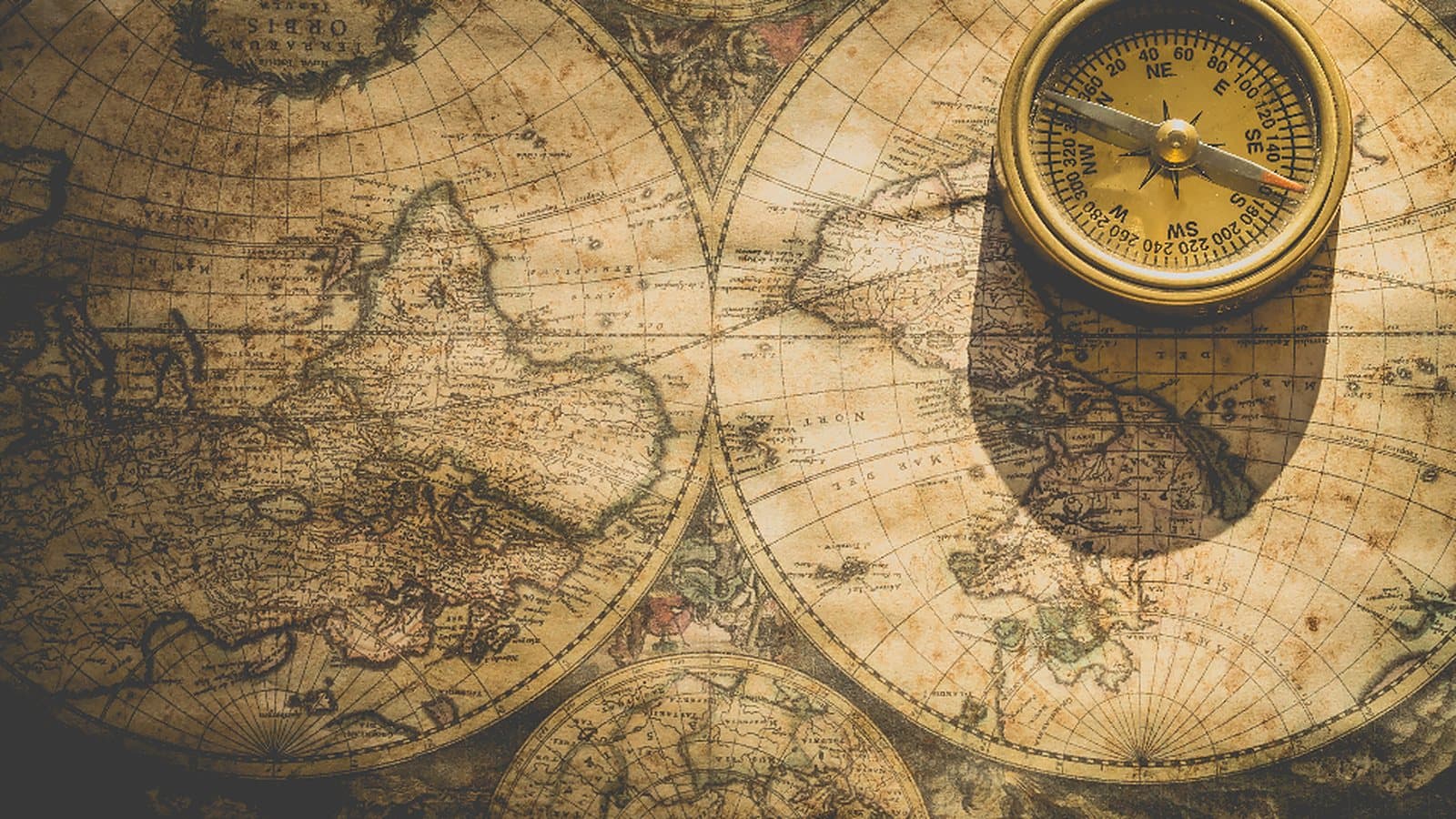 Mapa-múndi antigo em papel envelhecido, com uma bússola dourada apoiada em cima