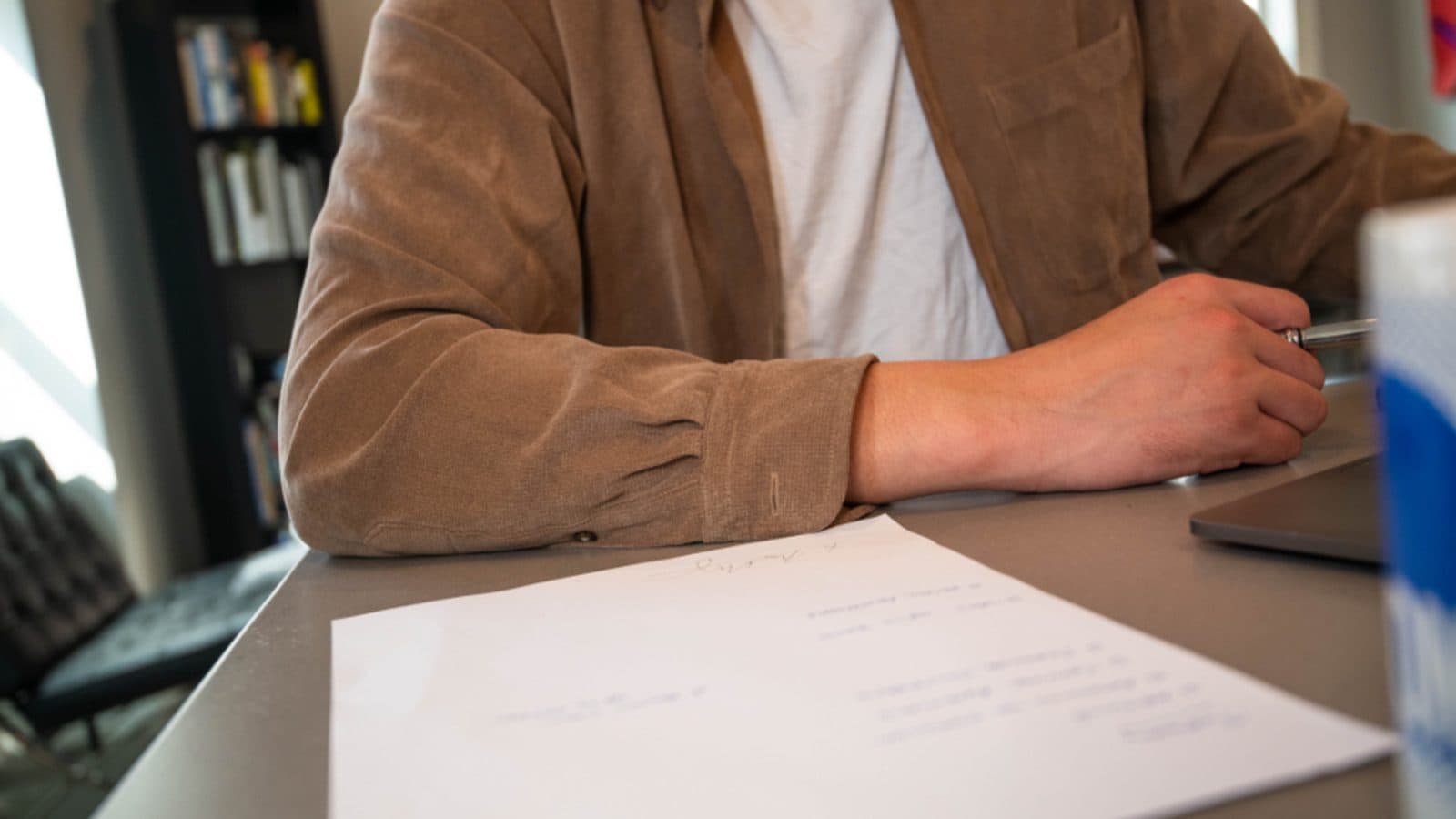 Pessoa sentada à mesa diante de um documento impresso